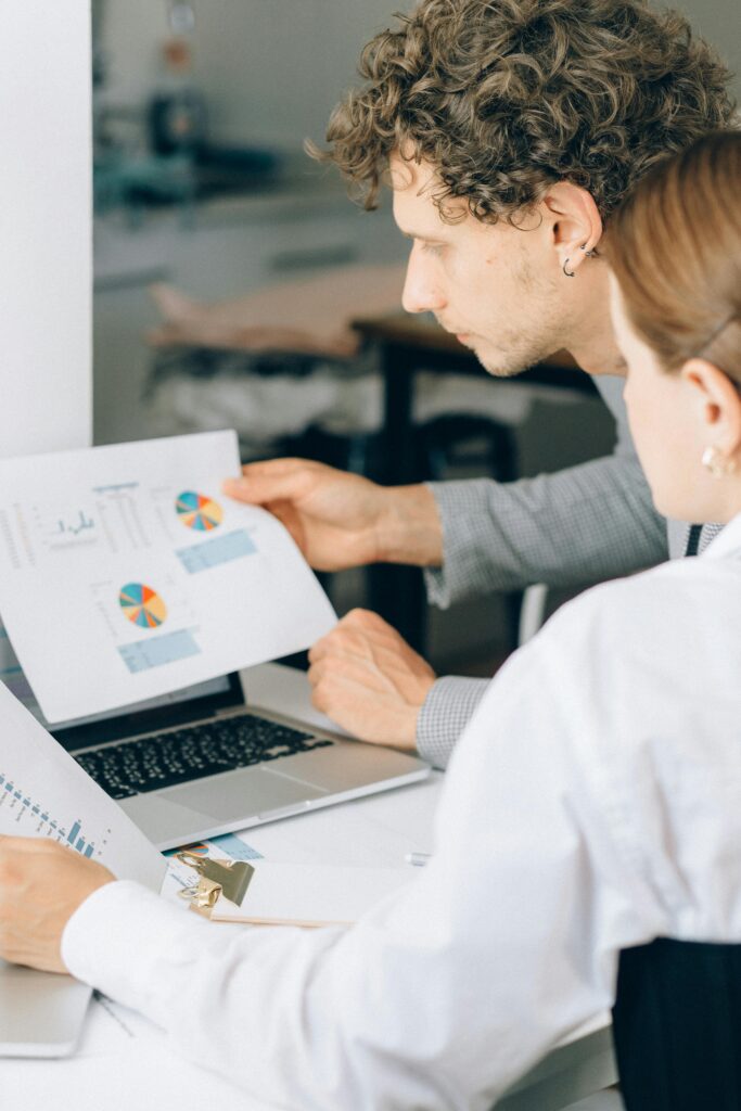 pexels-photo-8062287-8062287 Two business professionals reviewing financial charts and graphs in a modern office setting.